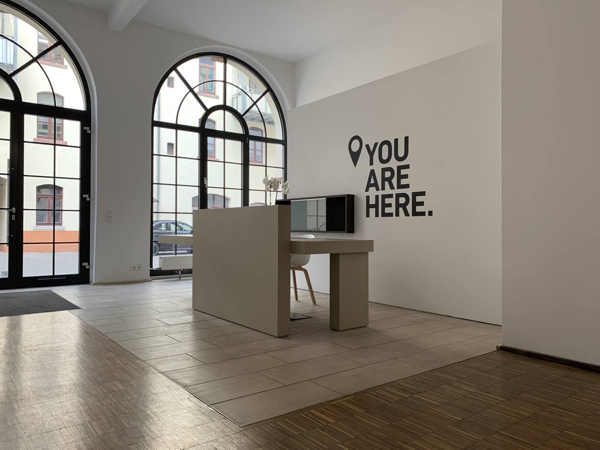 Eingangsbereich von ONE8Y in Wiesbaden mit Empfang und dem Schriftzug You are here