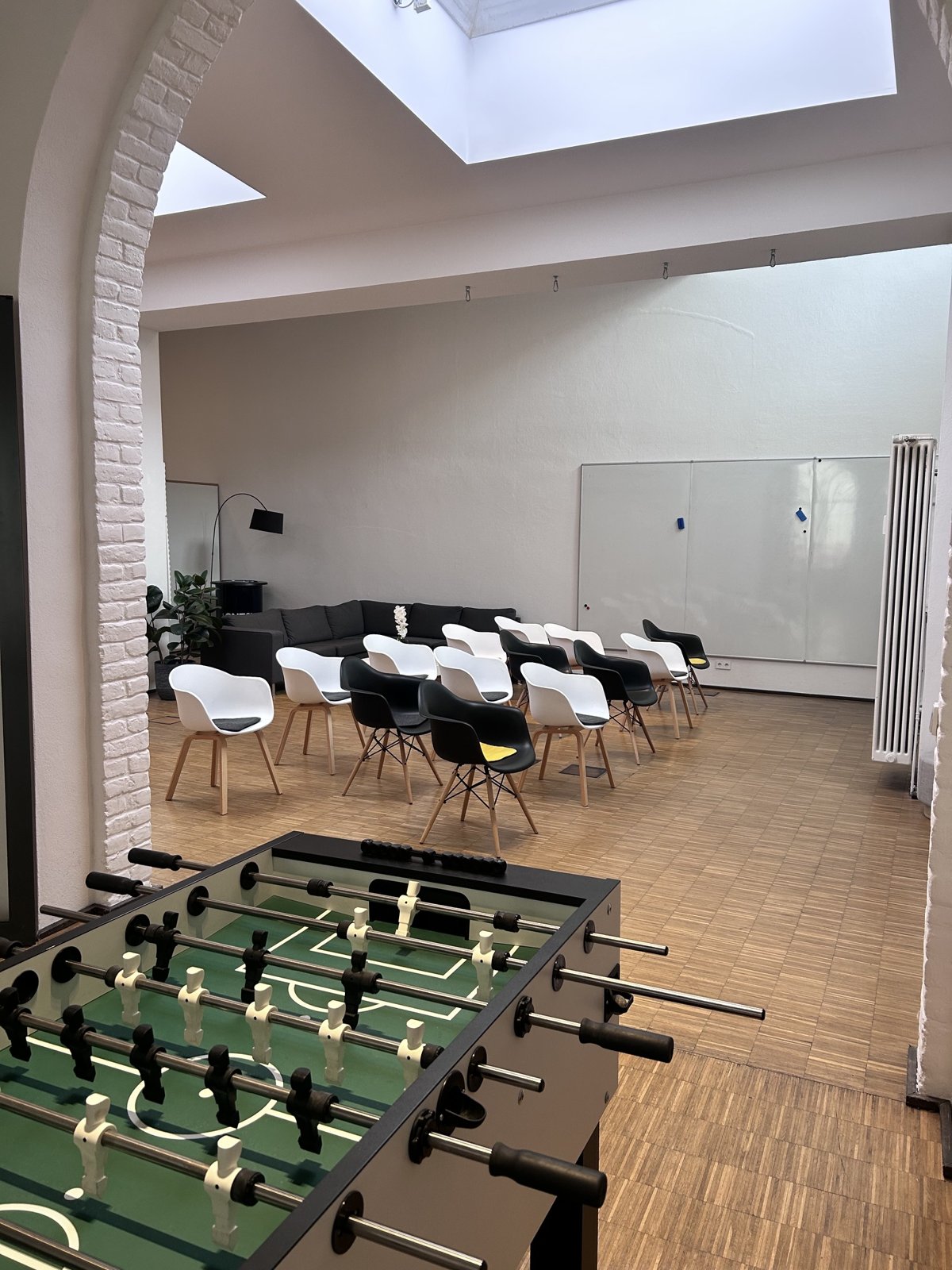 Seminarbereich bei ONE8Y mit bestuhlten Reihen, Whiteboard und Kicker im Vordergrund
